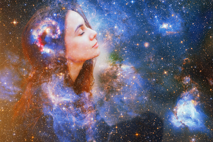 A woman's face is superimposed upon a star-studded sky filled with nebulae and galaxies.